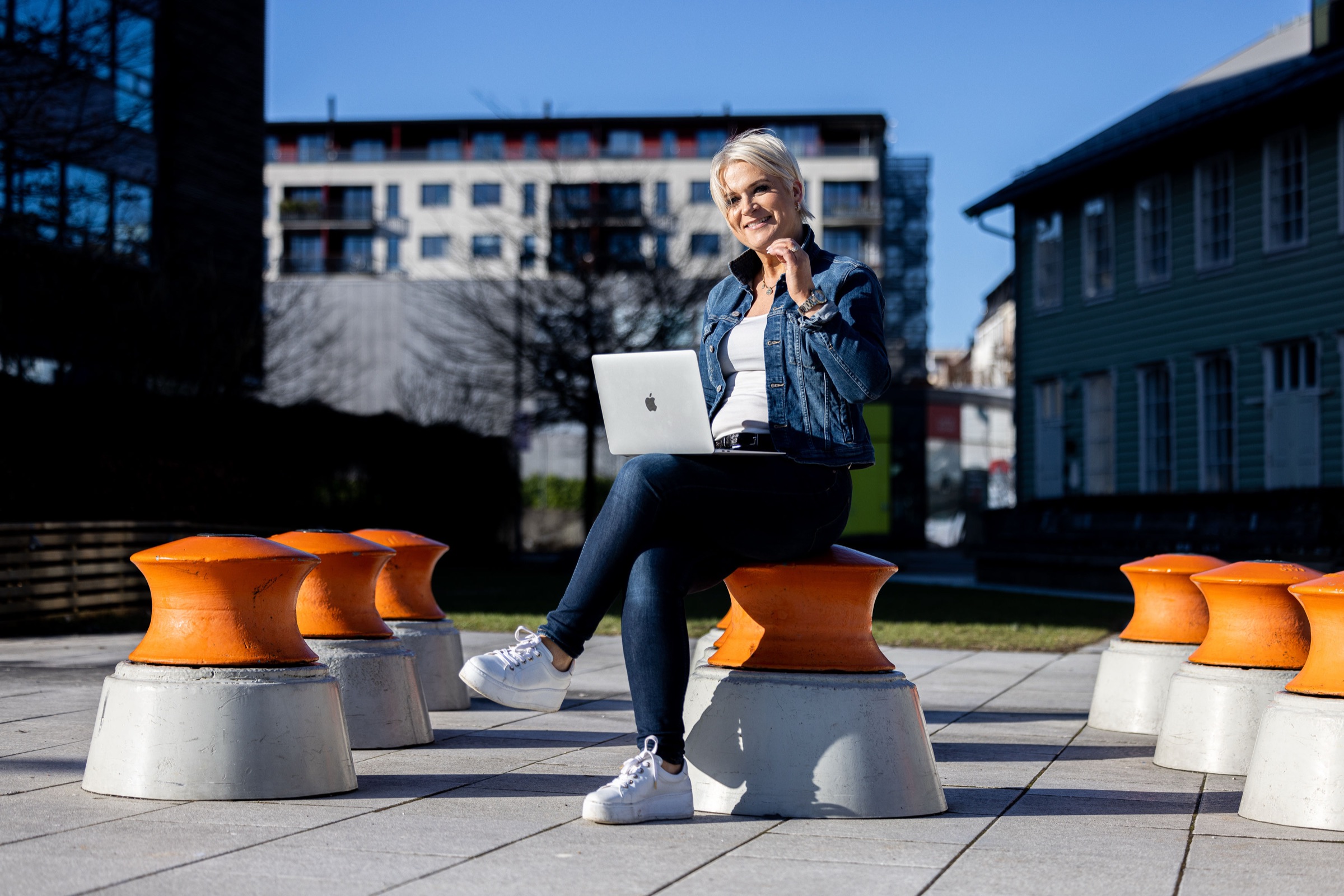 Jorunn Austgulen med PC på en oransje krakk utendørs i Bergen